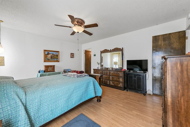 bedroom featuring hardwood / wood-style floors, ceiling fan, and a textured ceiling