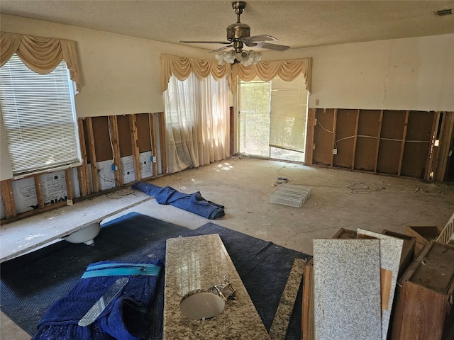 interior space with ceiling fan and a textured ceiling