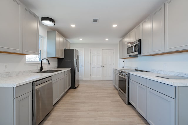 kitchen featuring gray cabinets, sink, light hardwood / wood-style floors, and stainless steel appliances