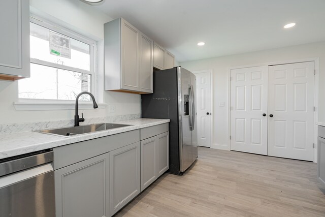 kitchen featuring gray cabinetry, light wood-type flooring, sink, and appliances with stainless steel finishes