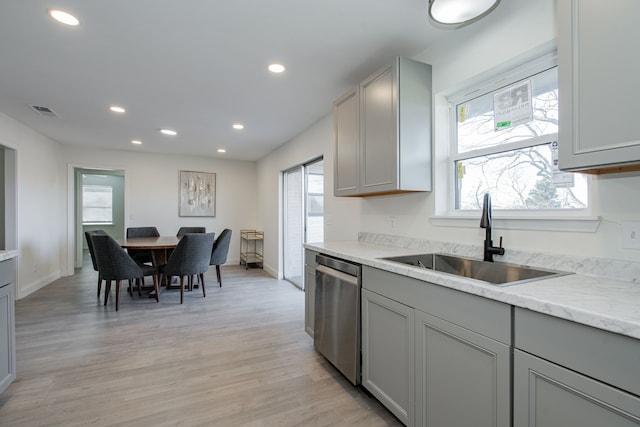 kitchen featuring sink, stainless steel dishwasher, gray cabinets, light stone countertops, and light wood-type flooring