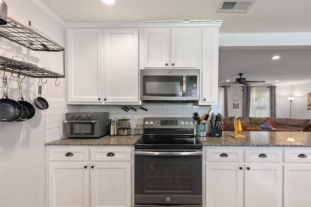 kitchen featuring ceiling fan, stainless steel appliances, dark stone countertops, crown molding, and white cabinets