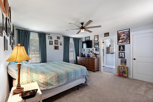 carpeted bedroom with ensuite bathroom and ceiling fan