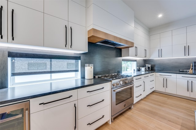 kitchen featuring wine cooler, decorative backsplash, white cabinetry, and high end stainless steel range