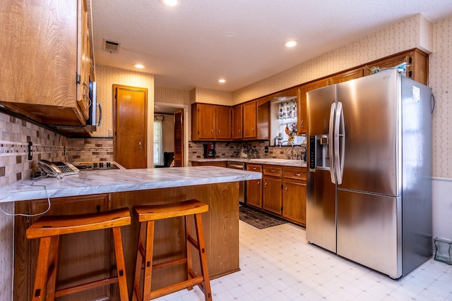 kitchen featuring kitchen peninsula, decorative backsplash, stainless steel appliances, and a breakfast bar area