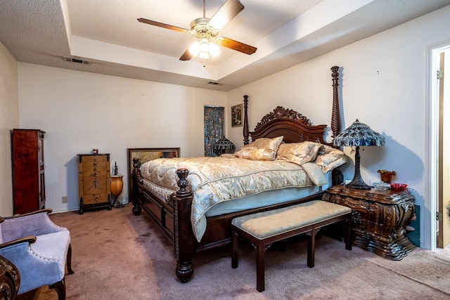 carpeted bedroom with a raised ceiling and ceiling fan