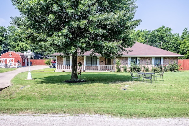 ranch-style house with covered porch, an outbuilding, and a front yard