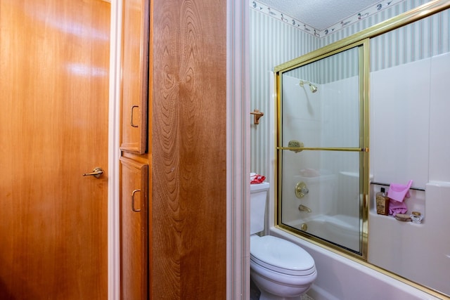 bathroom with a textured ceiling, toilet, and bath / shower combo with glass door