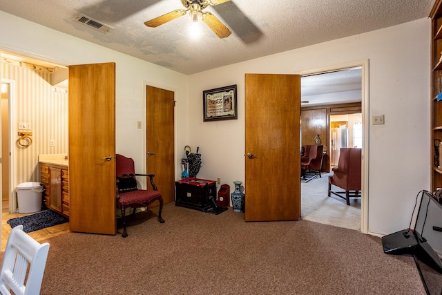 interior space with a textured ceiling, light colored carpet, and ceiling fan