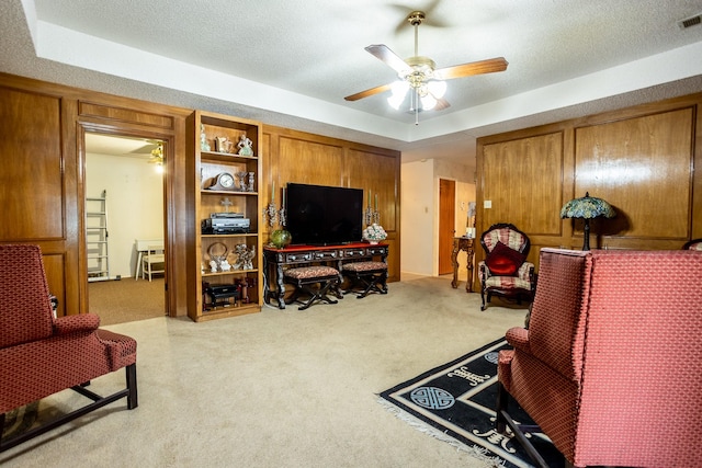 carpeted living room featuring ceiling fan, a textured ceiling, and a tray ceiling