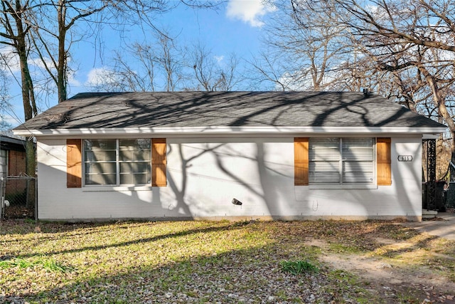 view of side of home featuring a yard, a shingled roof, and brick siding