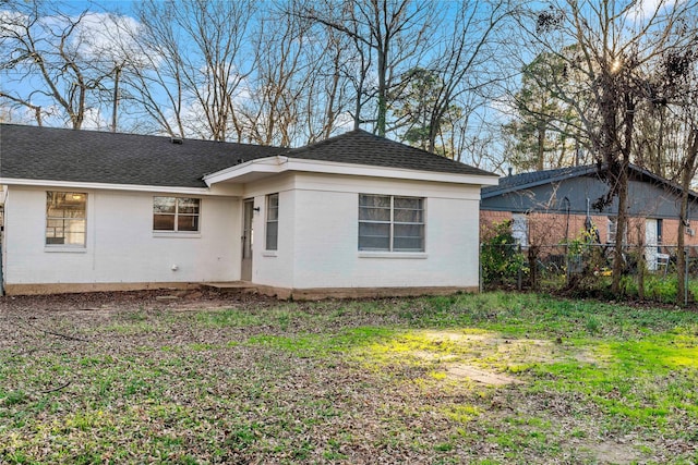 exterior space with brick siding, fence, a lawn, and roof with shingles