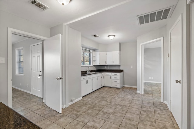 kitchen with dark countertops, a sink, and visible vents