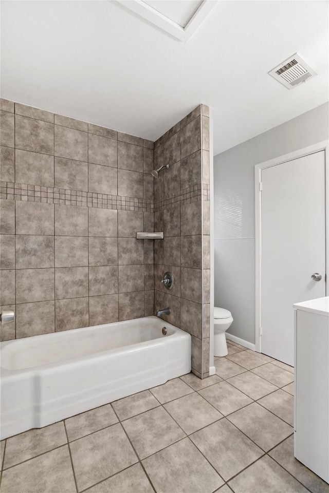 bathroom featuring tile patterned flooring, tiled shower / bath combo, and toilet