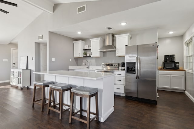 kitchen with white cabinets, a center island, wall chimney range hood, and stainless steel appliances