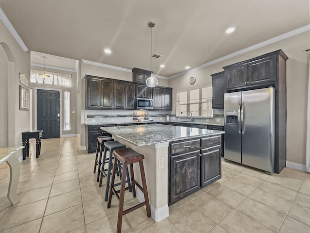 kitchen with appliances with stainless steel finishes, a kitchen island, pendant lighting, and light tile patterned flooring