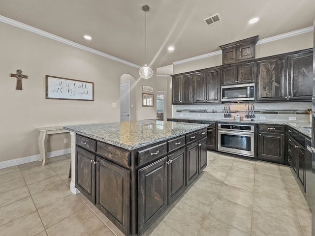 kitchen featuring stainless steel appliances, a kitchen island, hanging light fixtures, and light stone counters