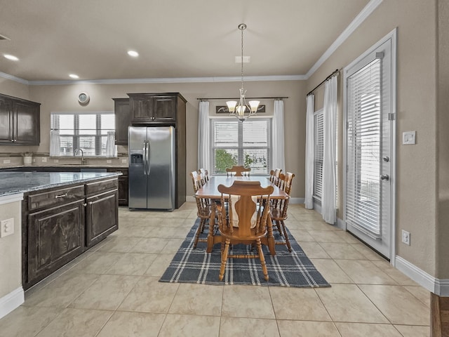 tiled dining space featuring a notable chandelier, crown molding, plenty of natural light, and sink