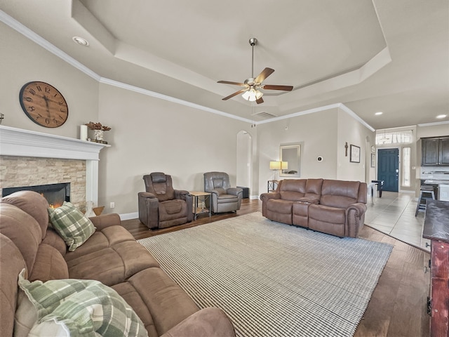 living room featuring light wood-type flooring, a tray ceiling, ceiling fan, and ornamental molding