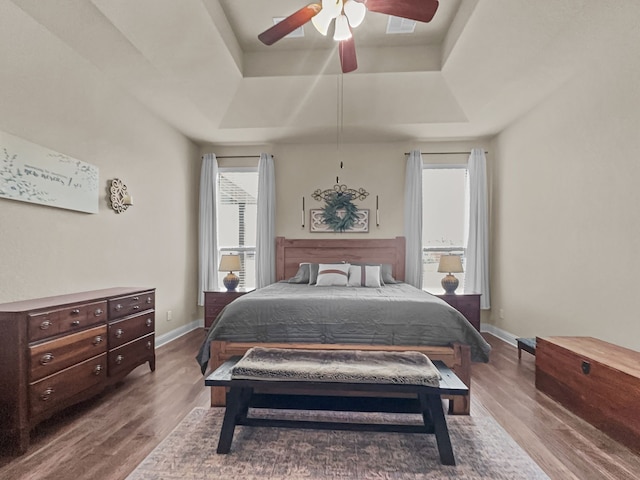 bedroom featuring hardwood / wood-style flooring, ceiling fan, and a tray ceiling