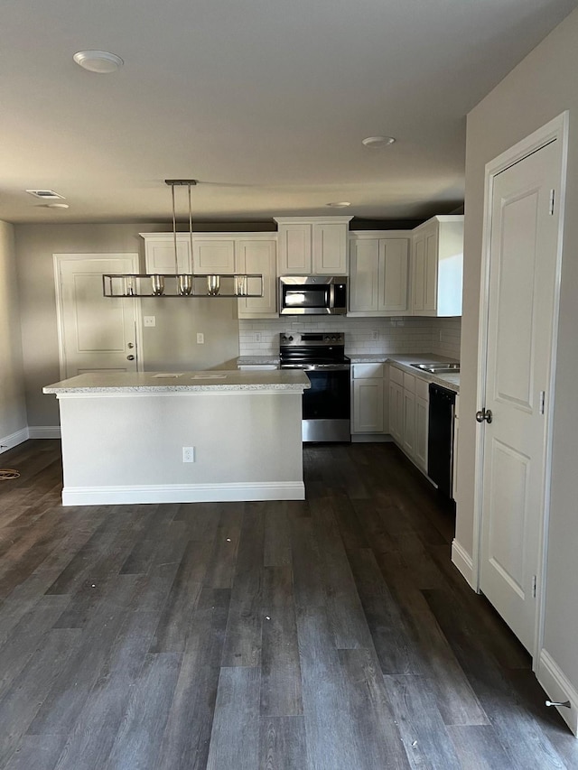 kitchen featuring decorative light fixtures, white cabinetry, backsplash, and appliances with stainless steel finishes