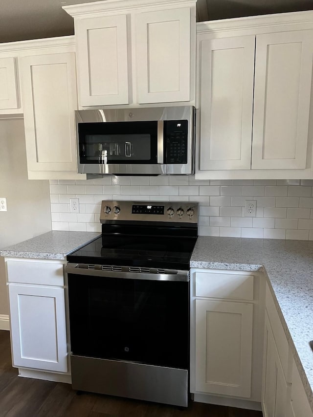 kitchen featuring white cabinetry, dark hardwood / wood-style flooring, light stone countertops, and appliances with stainless steel finishes