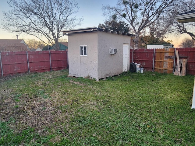 outdoor structure at dusk featuring a lawn and a wall mounted air conditioner