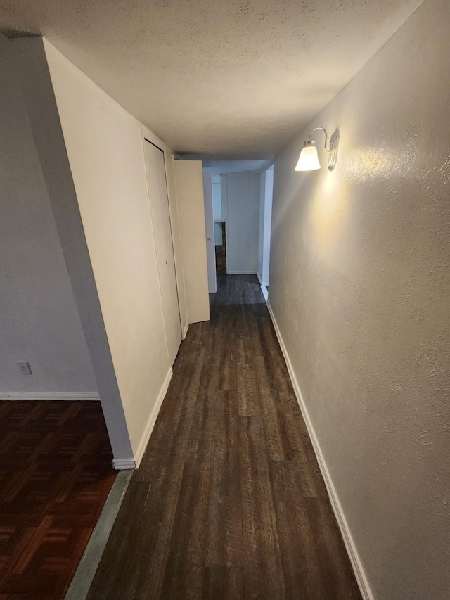 hallway with dark hardwood / wood-style floors and a textured ceiling