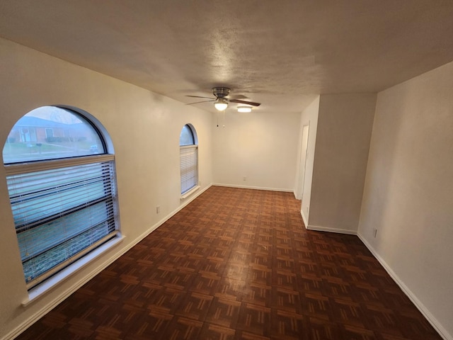 unfurnished room with ceiling fan, a textured ceiling, and dark parquet floors