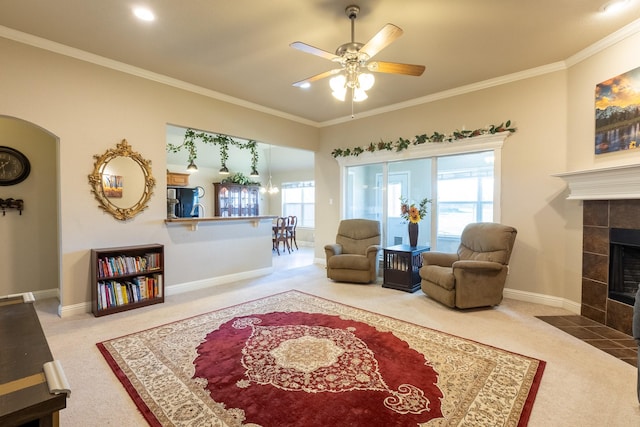 carpeted living room with a fireplace, crown molding, ceiling fan, and a healthy amount of sunlight