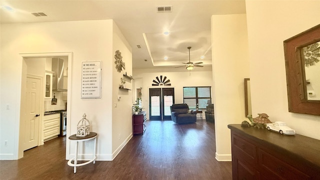 corridor with dark hardwood / wood-style flooring and a raised ceiling