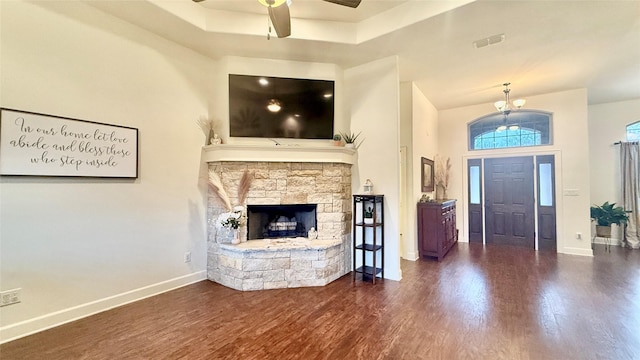 living room featuring dark wood-type flooring, ceiling fan, a tray ceiling, and a fireplace