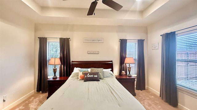 carpeted bedroom featuring ceiling fan and a raised ceiling