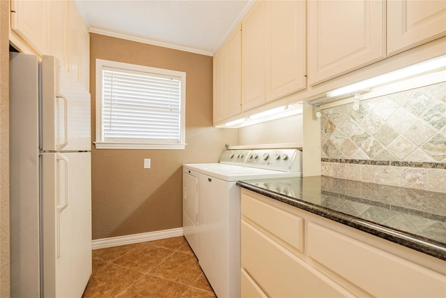 laundry area featuring baseboards, crown molding, cabinet space, washing machine and dryer, and light tile patterned flooring