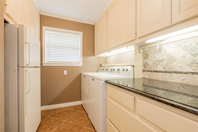 clothes washing area with cabinets, crown molding, washing machine and clothes dryer, and tile patterned floors