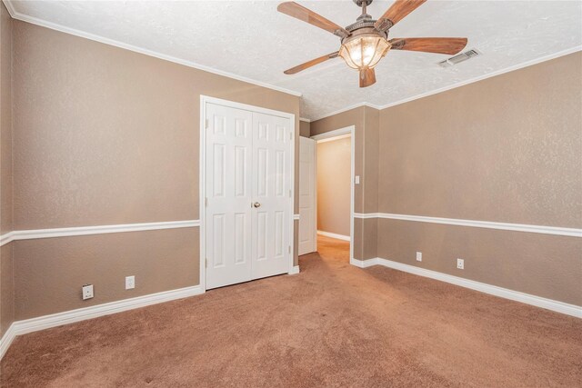 unfurnished bedroom with crown molding, a closet, a textured ceiling, and carpet