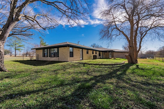 rear view of property featuring central AC unit and a lawn