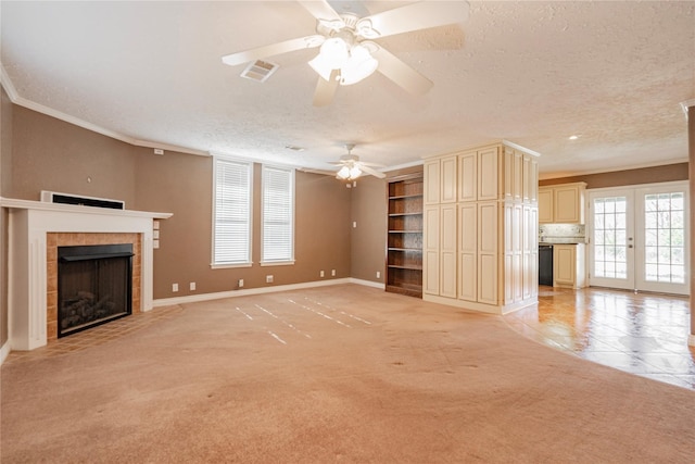 unfurnished living room with ceiling fan, a fireplace, a textured ceiling, ornamental molding, and visible vents