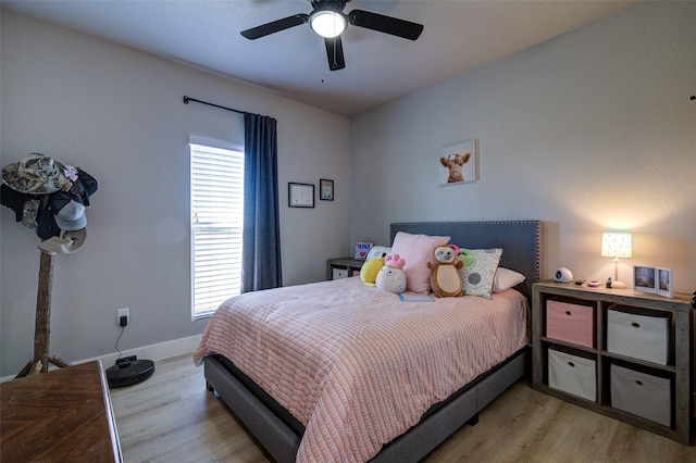 bedroom featuring ceiling fan, light hardwood / wood-style floors, and multiple windows