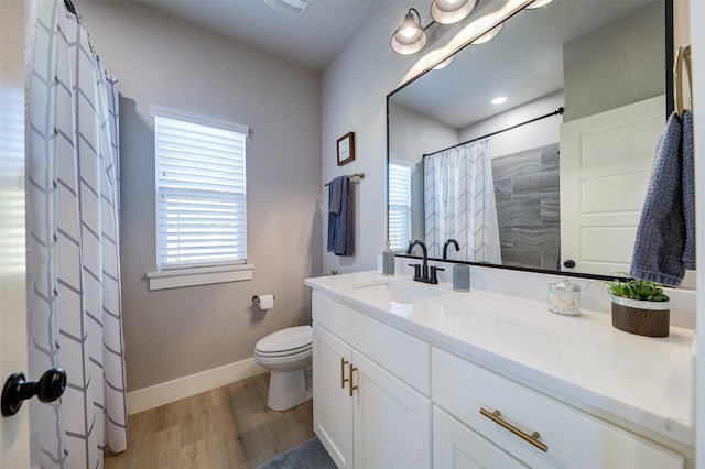 bathroom with vanity, plenty of natural light, toilet, and wood-type flooring