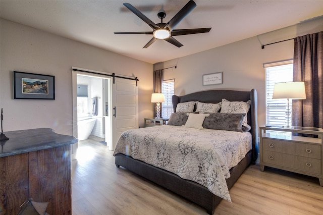 bedroom featuring light hardwood / wood-style floors, a barn door, and ceiling fan