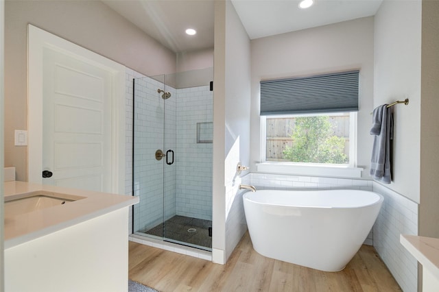 bathroom featuring vanity, separate shower and tub, hardwood / wood-style floors, and tile walls