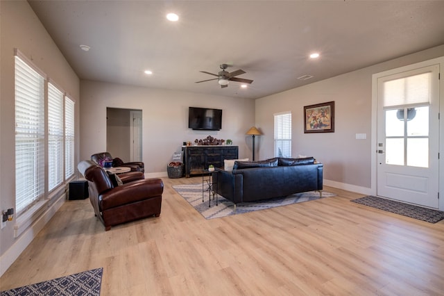 living room featuring ceiling fan, a fireplace, a healthy amount of sunlight, and light wood-type flooring