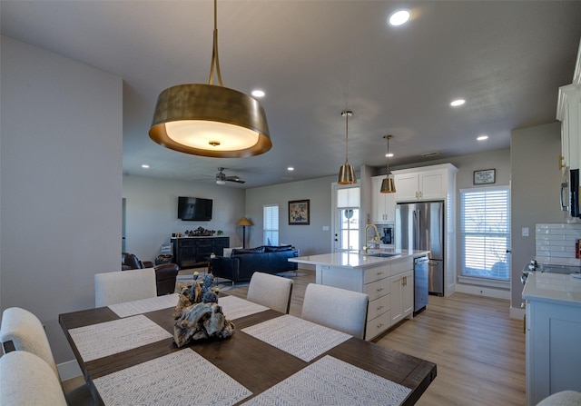 dining room with ceiling fan, sink, and light wood-type flooring