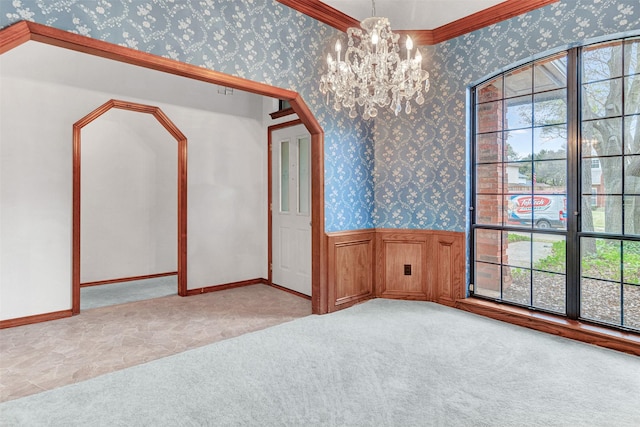 empty room featuring light colored carpet, a chandelier, and ornamental molding