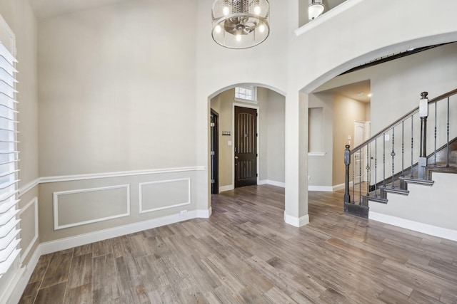 empty room featuring a towering ceiling, a notable chandelier, and hardwood / wood-style flooring