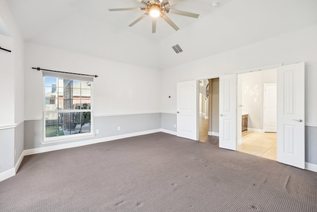 unfurnished bedroom with ensuite bath, ceiling fan, light carpet, and vaulted ceiling