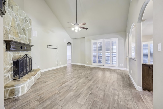 unfurnished living room featuring a fireplace, light wood-type flooring, high vaulted ceiling, and ceiling fan