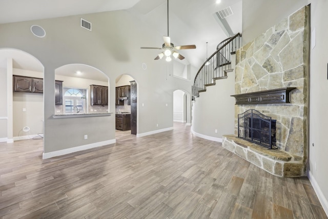 unfurnished living room with ceiling fan, wood-type flooring, a fireplace, and high vaulted ceiling