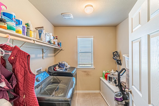 laundry area with separate washer and dryer, light tile patterned floors, and a textured ceiling